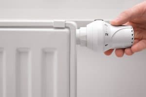 Hand adjusting the temperature of heating radiator