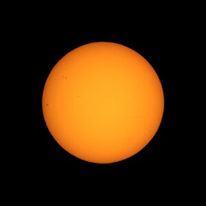 Sun seen with telescope from planet Earth, with sunspots visible as dark spots compared to surrounding regions
