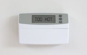 Vintage digital thermostat hanging on a white wall displaying 