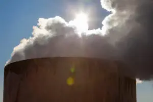 Smoke coming from the top of a chimney and blocking out the sun.