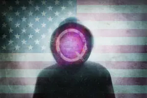 QAnon conspiracy theory concept. Of a hooded figure with the Q symbol. Over layered with the United States flag. with a blurred, grunge, abstract edit