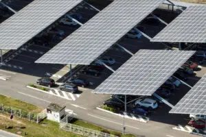 Aerial view of solar panels installed over parking lot with parked cars for effective generation of clean energy