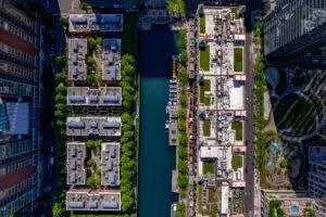 The bird's eye view of the building roofs and river surrounded by green vegetation.