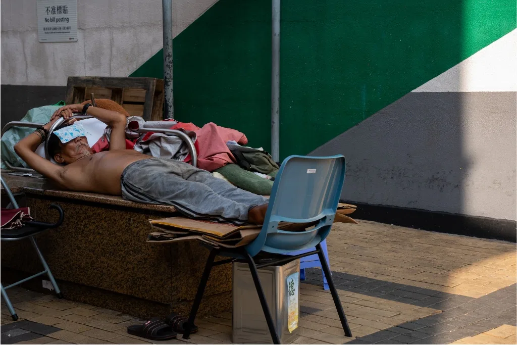 A man lies down and wears a cooling patch on his forehead during a humid heatwave in Hong Kong.