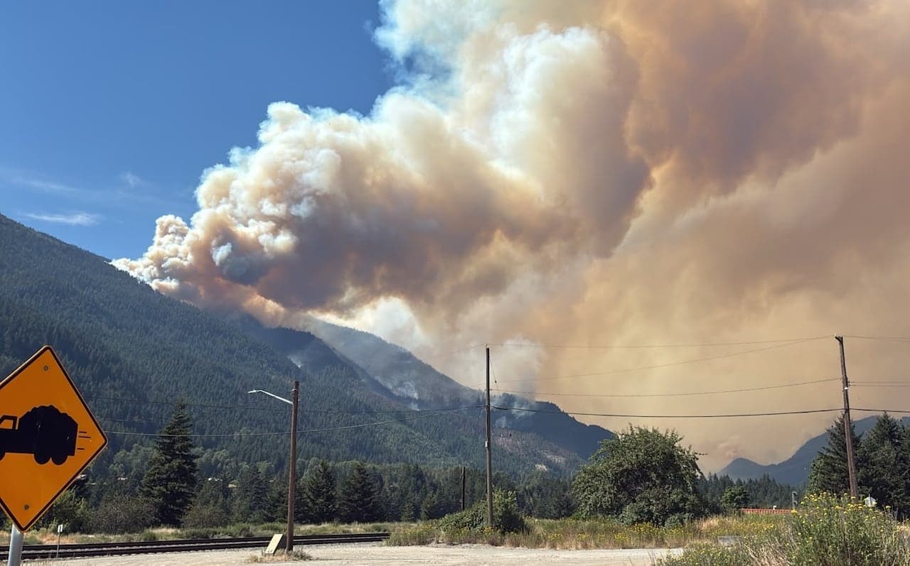 Smoke billows up from a forested mountain.