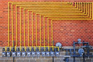 Row of natural gas meters with yellow pipes on building brick wall