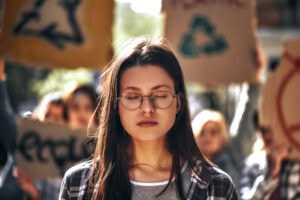 Dreaming about clean earth young woman in eyewear keeping eyes closed while standing outdoors