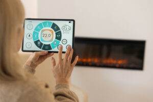Navigating a smart home tablet app in a cozy living room with fireplace on background. 